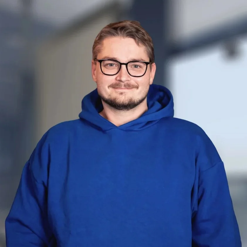 Portrait von Pascal Langhals vor der hellen Fensterfront im Büro
