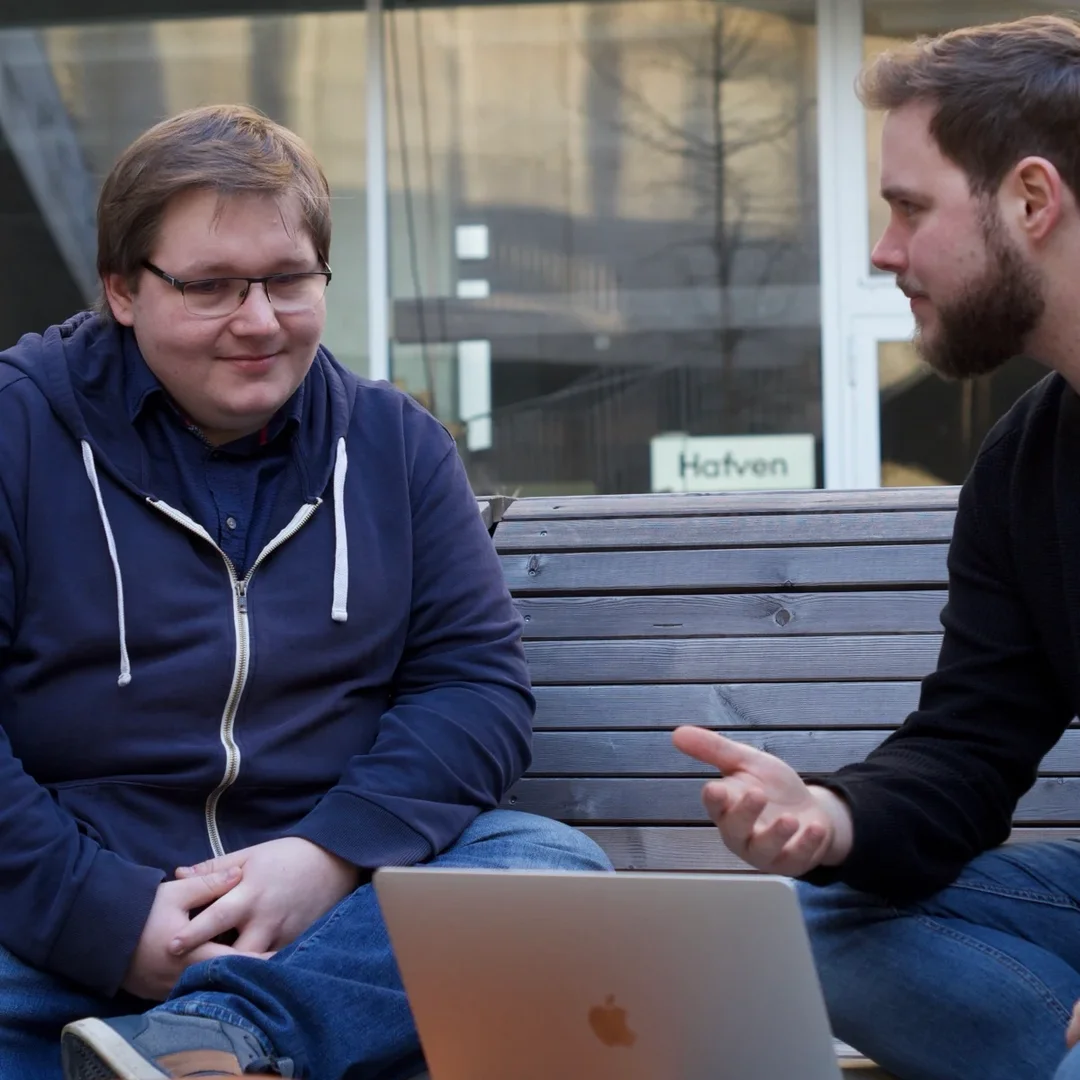 Die Gründer Tim und Meik Rücker im Gespräch auf einer Holzbank