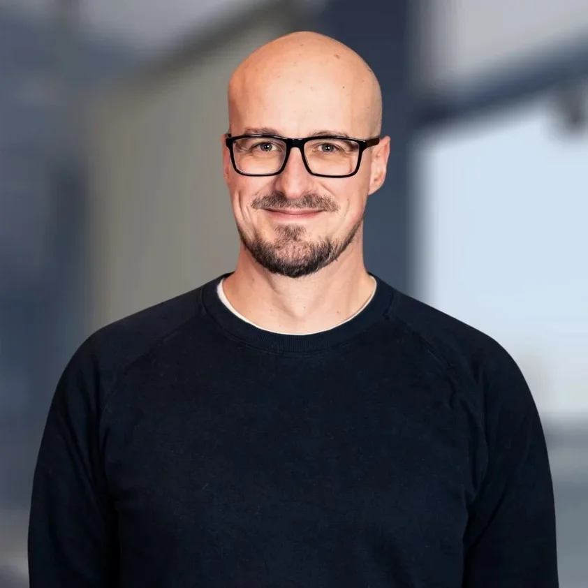 Portrait von Kevin Puls vor der hellen Fensterfront im Büro