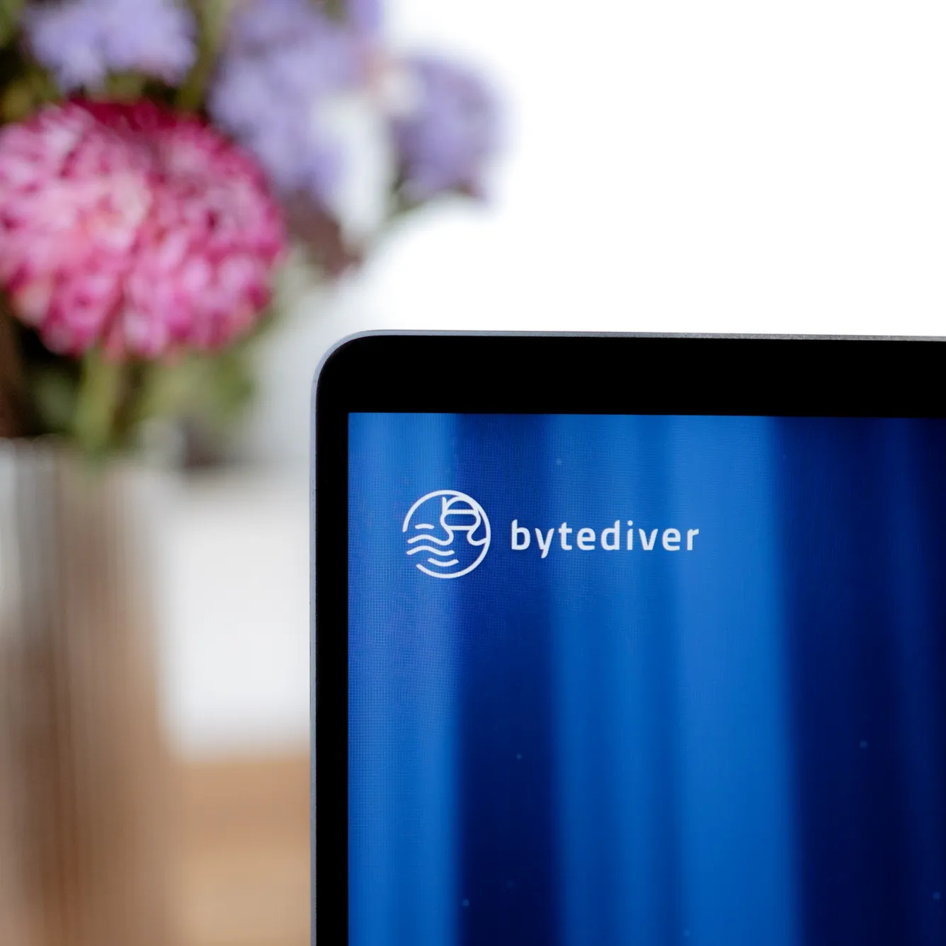 Ein Bildschirm mit dem Logo von bytediver, davor ein Strauß Blumen